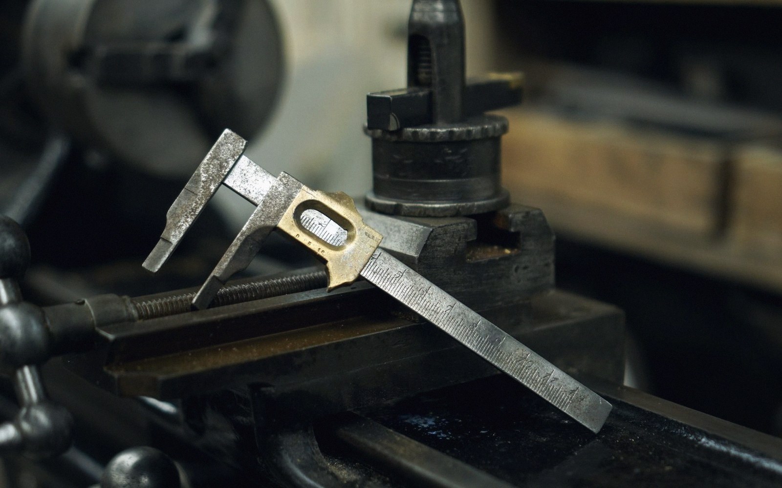 A vernier caliper resting on the metal bed of a lathe machine